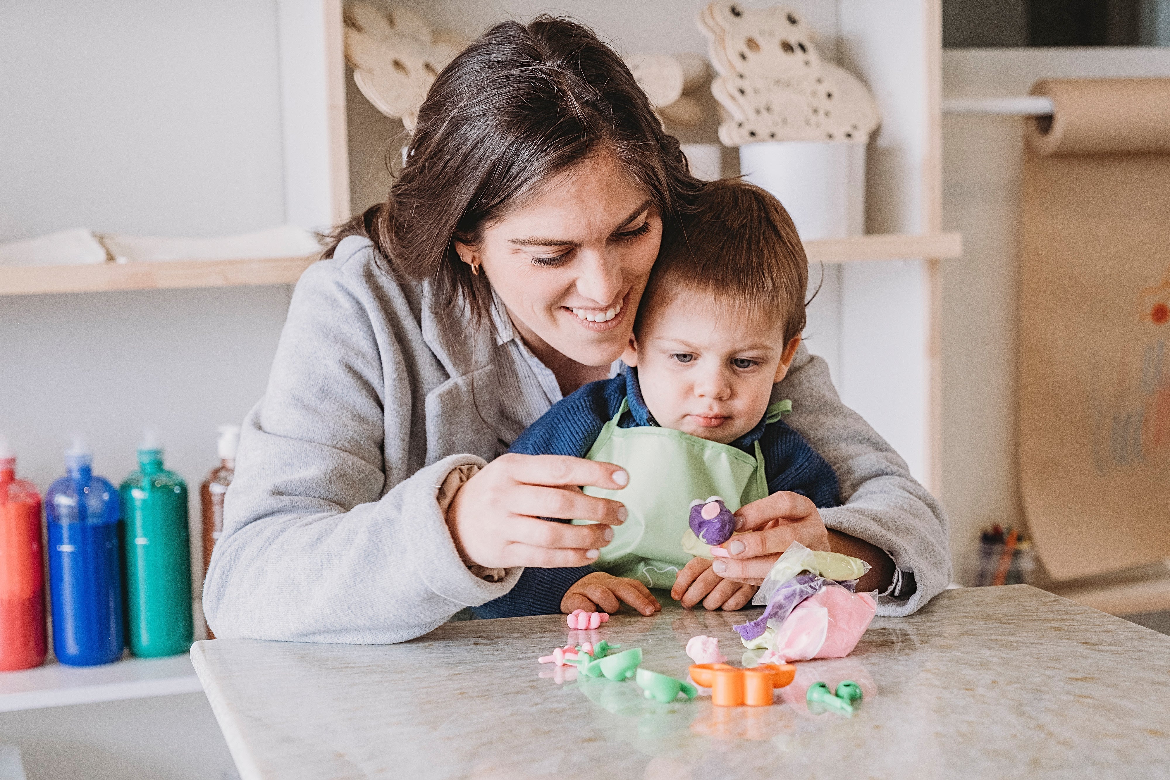 Niños creando con materiales abiertos como cartones, pinturas y elementos reciclados en un ambiente creativo en casa.