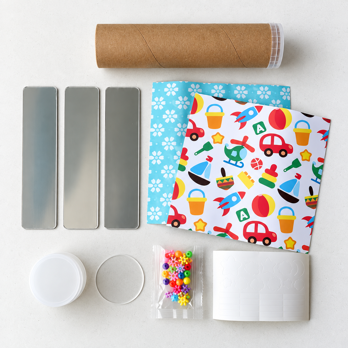Contenido del Kit Arma tu Caleidoscopio: tubo de cartón, 3 espejos, papel con diseño, cuentas de colores, vaso y disco transparente y stickers