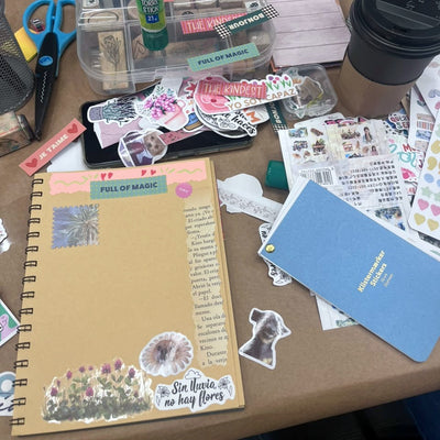 Diario creativo decorado con stickers, washitape y recortes, junto a timbres y materiales del taller de journaling para grupos